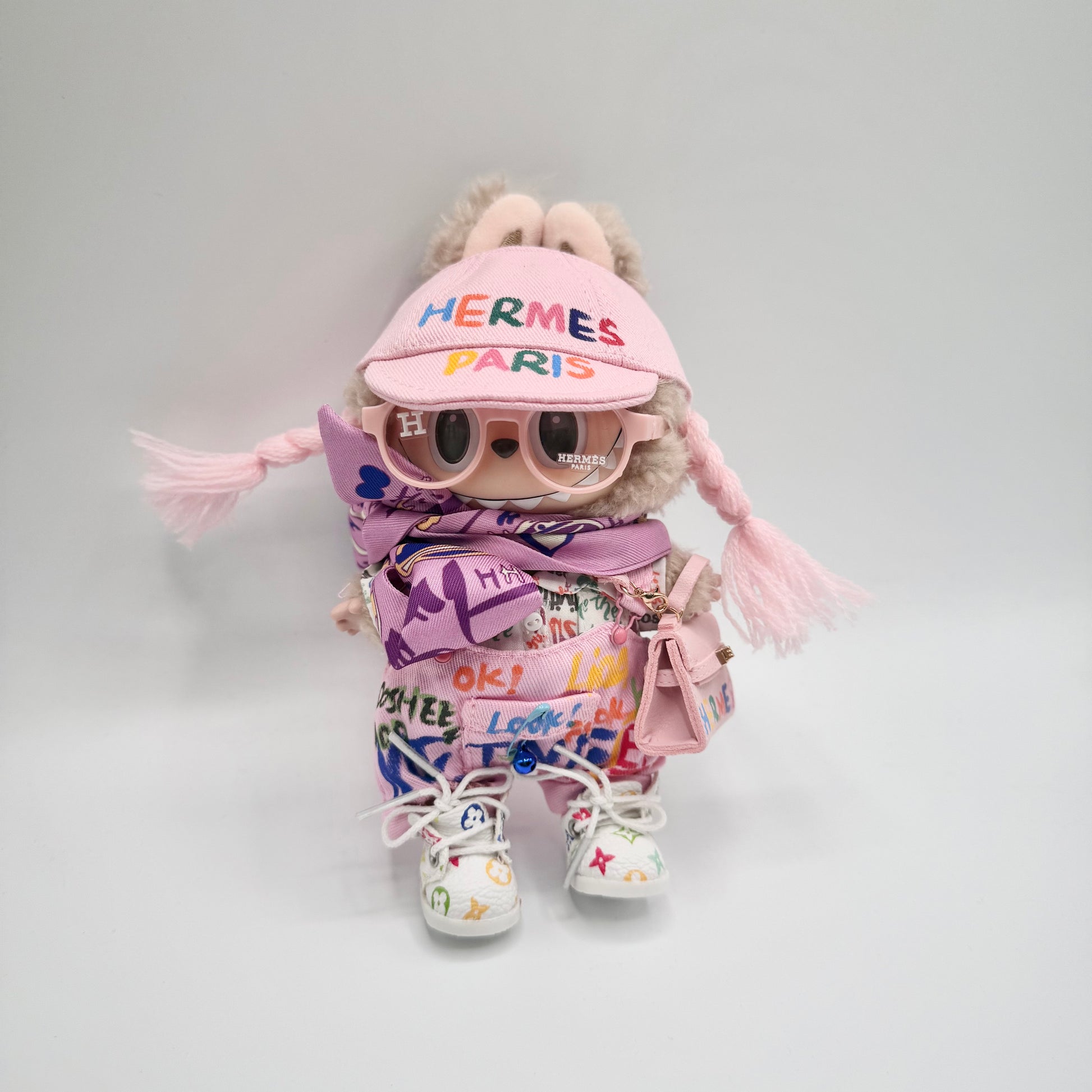 "Labubu doll outfit with pink Hermes visor, matching sunglasses, purple scarf, rainbow graffiti jumpsuit, white sneakers, and pink mini handbag – luxury streetwear style for collectible dolls"